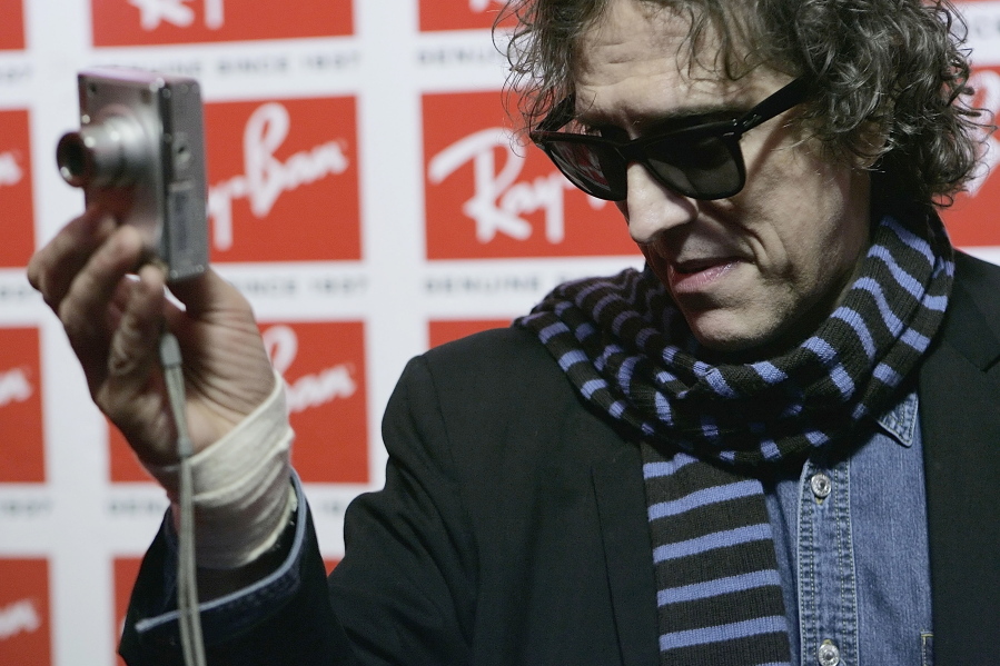 Photographer Mick Rock uses a point and shoot camera to photograph the photographers at the Uncut Ray-Ban Wayfarer Sessions event, on Nov. 15, 2006, at Irving Plaza in New York. Photographer Mick Rock, whose iconic portraits of rock stars saw him dubbed "the man who shot the 70s," has died.