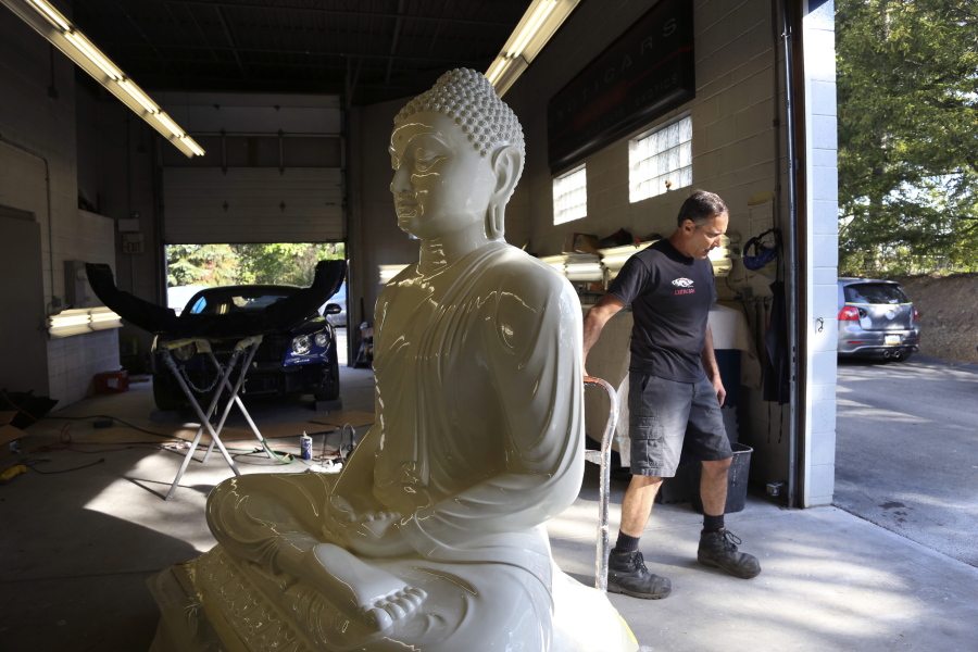 Dave Ley, co-owner of Exoticars, an auto restoration shop specializing in classic vehicles, pulls a restored statue of the Buddha outside Oct. 11 in McCandless, Pa. Workers repaired and repainted the figure for the Pittsburgh Buddhist Center.