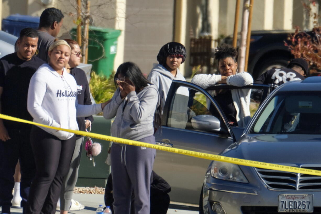 Neighbors react near a home where five bodies were found in the city of Lancaster in the high desert Antelope Valley north of Los Angeles, Monday, Nov. 29, 2021. A Los Angeles County Sheriff's Department statement says deputies found a woman, a girl and three boys with gunshot wounds and paramedics pronounced them dead at the scene. The department says the children's father showed up at the Lancaster sheriff's station and was arrested on suspicion of five murders after being interviewed by detectives. (AP Photo/Ringo H.W.
