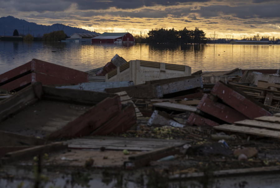 Debris is piled up as farms are surrounded by floodwaters caused by heavy rains and mudslides in Abbotsford, British Columbia, Friday, Nov. 19, 2021.