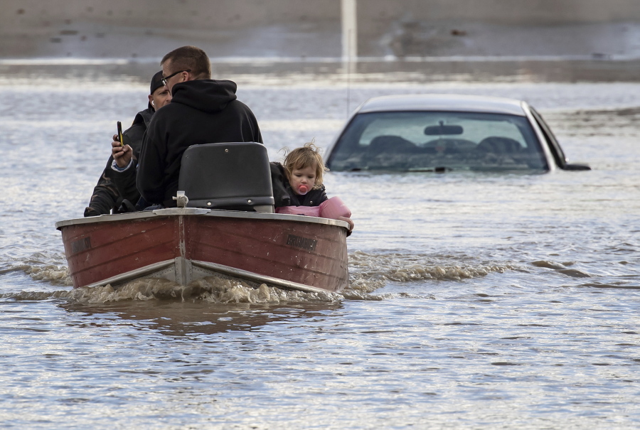 People, including a toddler and dog who were stranded by high water due to flooding are rescued by a volunteer operating a boat in Abbotsford, British Columbia, on Tuesday, Nov. 16, 2021.