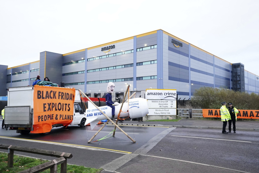 Activists from Extinction Rebellion block the entrance to the Amazon fulfilment centre, preventing lorries from entering or leaving on Black Friday, the global retail giant's busiest day of the year, in Tilbury, England,  Friday Nov. 26, 2021. The group has targeted Amazon sites in Doncaster, Darlington, Dunfremline, Newcastle, Manchester, Peterborough, Derby, Coventry, Rugeley, Dartford, Bristol, Tilbury and Milton Keynes.