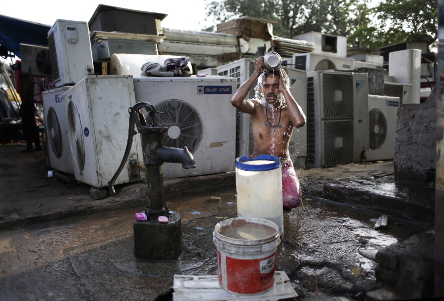 FILE - A migrant daily wage worker bathes at a public well pump on a hot morning in New Delhi, India, Tuesday, May 17, 2016. Scorching summer temperatures, hovering well over 40 degrees Celcius, (104 Fahrenheit) are making life extremely tough for millions of poor across north India. Without access to air conditioning and sometimes even an electric fan, they struggle to cope with the heat in their inadequate homes.