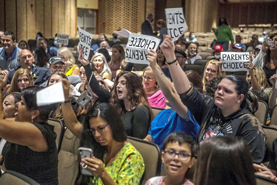 FILE - People hold signs and chant during a meeting of the North Allegheny School District school board regarding the district's mask policy, at at North Allegheny Senior High School in McCandless, Pa., Aug. 25, 2021. School board candidates opposing mask mandates and lessons about racism in U.S. history won in red states and some politically divided districts but often came up short in their bids to shape policy for school districts over the newest culture war issue.