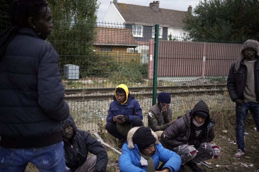 FILE- Migrants wait for food distribution at a camp in Calais, northern France, Thursday, Oct. 14, 2021. The price to cross the English Channel varies according to the network of smugglers, between 3,000 and 7,000 euros. Often, the fee also includes a very short-term tent rental in the windy dunes of northern France and food cooked over fires that sputter in the rain that falls for more than half the month of November in the Calais region.