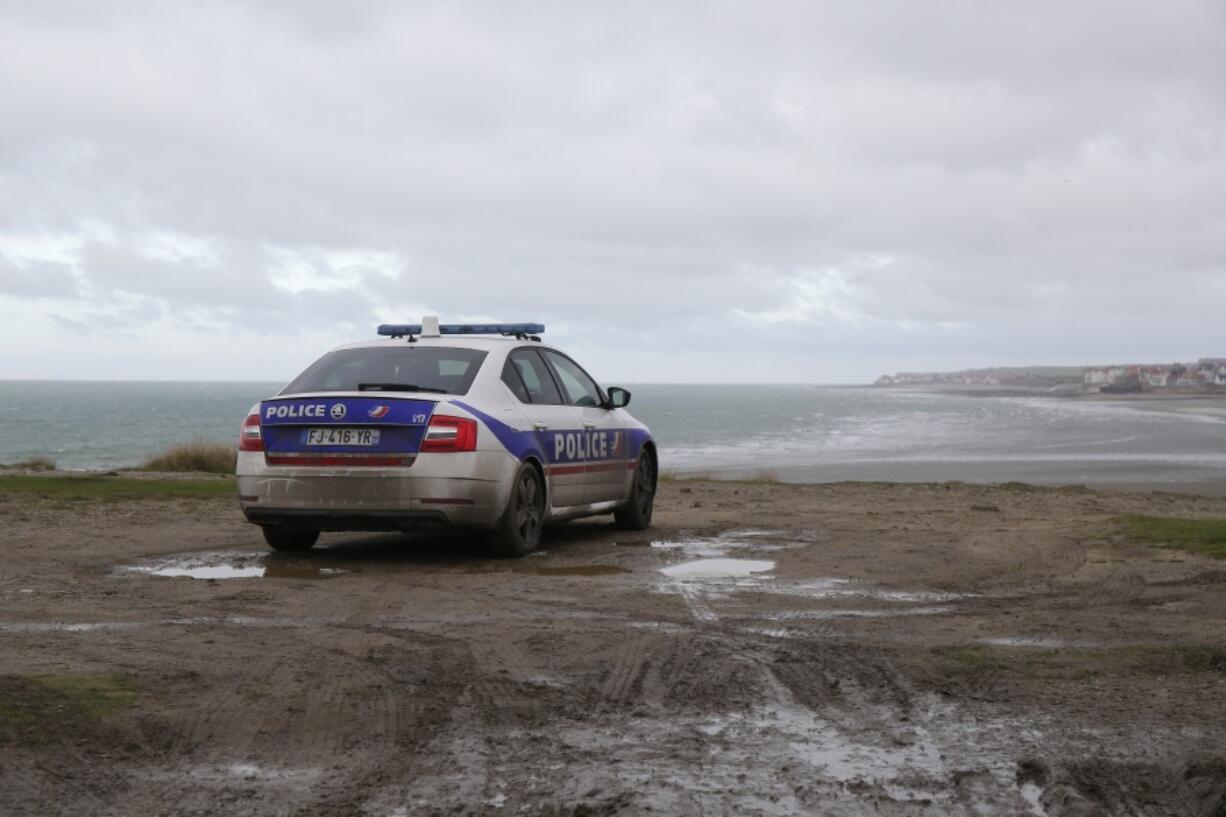 FILE- A police car parks over the shore in Wimereux, northern France, Thursday, Nov. 25, 2021 in Calais, northern France. The price to cross the English Channel varies according to the network of smugglers, between 3,000 and 7,000 euros. Often, the fee also includes a very short-term tent rental in the windy dunes of northern France and food cooked over fires that sputter in the rain that falls for more than half the month of November in the Calais region.