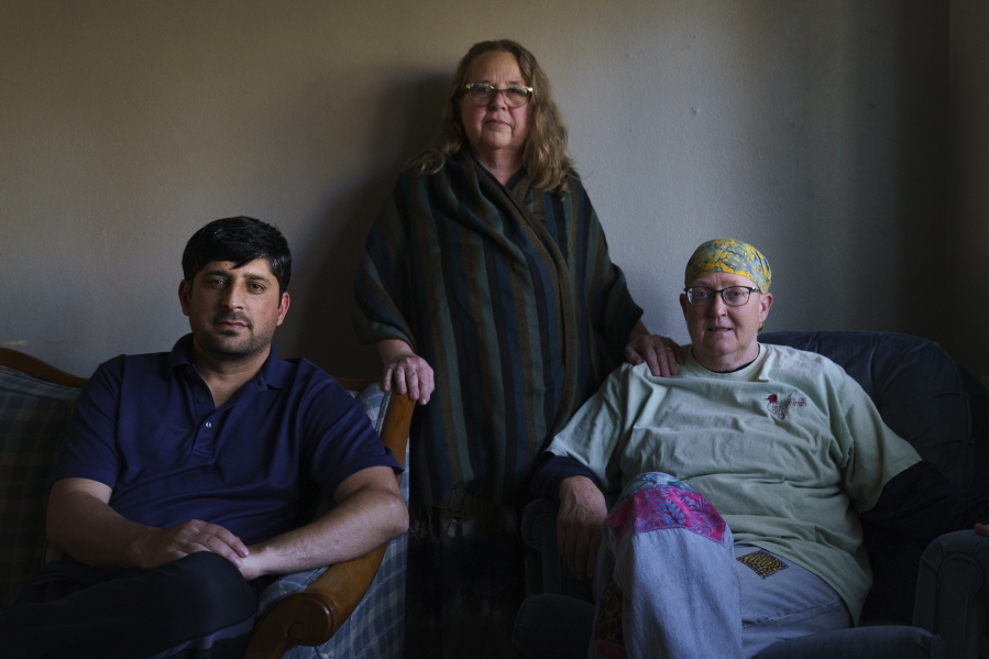 Ihsanullah Patan, left, a horticulturist and refugee from Afghanistan, sits for a portrait with Caroline Clarin, right, whom he worked with in Afghanistan, and her wife, Sheril Raymond, at his home in Fergus Falls, Minn., Friday, Oct. 29, 2021. A U.S. Department of Agriculture adviser in Afghanistan, Clarin along with her wife have been using their own time and money to get Afghans who worked for her program out of the country. Those who have started their life in the remote town of Fergus Falls near the North Dakota border say they consider them family.