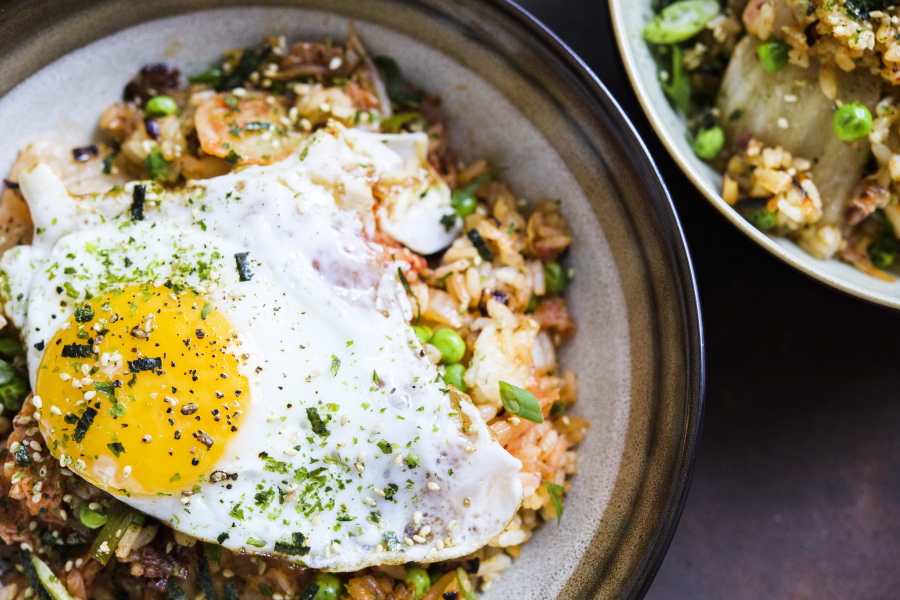 This image released by Milk Street shows a recipe for kimchi and bacon-fried rice, topped with a fried egg and sprinkled with furikake.
