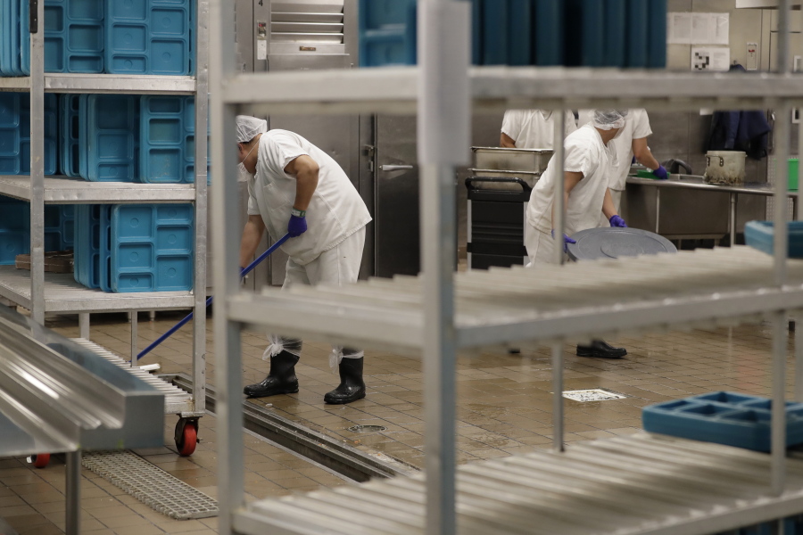 FILE - Workers are shown in the kitchen of The GEO Group's immigration detention center in Tacoma, Wash., during a media tour, Sept. 10, 2019. After a federal jury determined on Oct. 27, 2021, that detainee workers were entitled to minimum wage for cooking, cleaning and other work they perform, the company suspended the work program pending an appeal, rather than increase the detainees' pay. (AP Photo/Ted S.