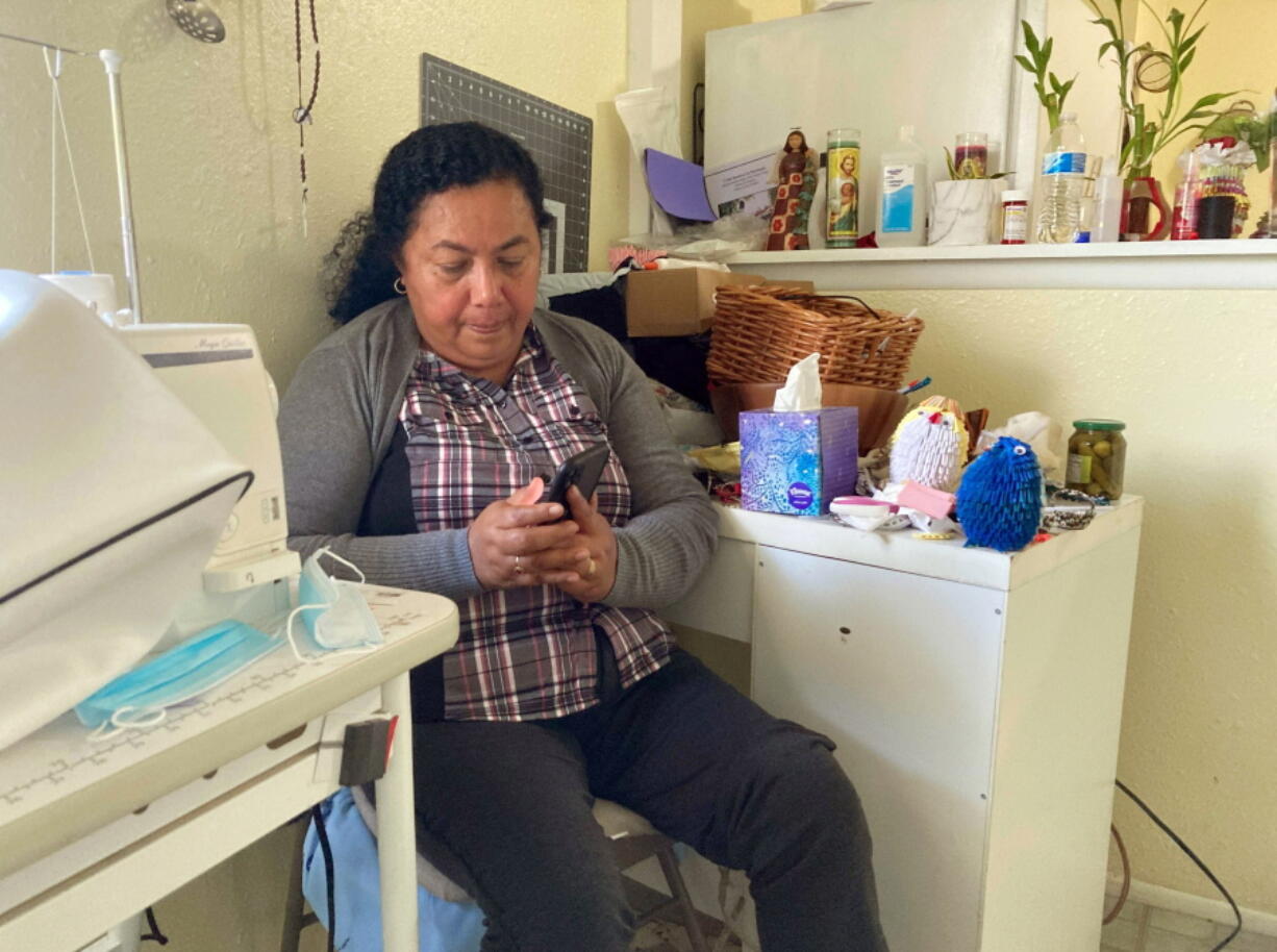 Rosalidia Dardon, 54, looks at a picture of her daughter in El Salvador as she sits in a refugee house in Texas, awaiting asylum or a protected immigration status on Nov. 4, 2021. At least seven statehouses have considered or left pending legislation this year to replace the term "illegal," "alien," or both from state laws referencing immigrants. Dardon knows from personal experience why the language surrounding immigration is so important.