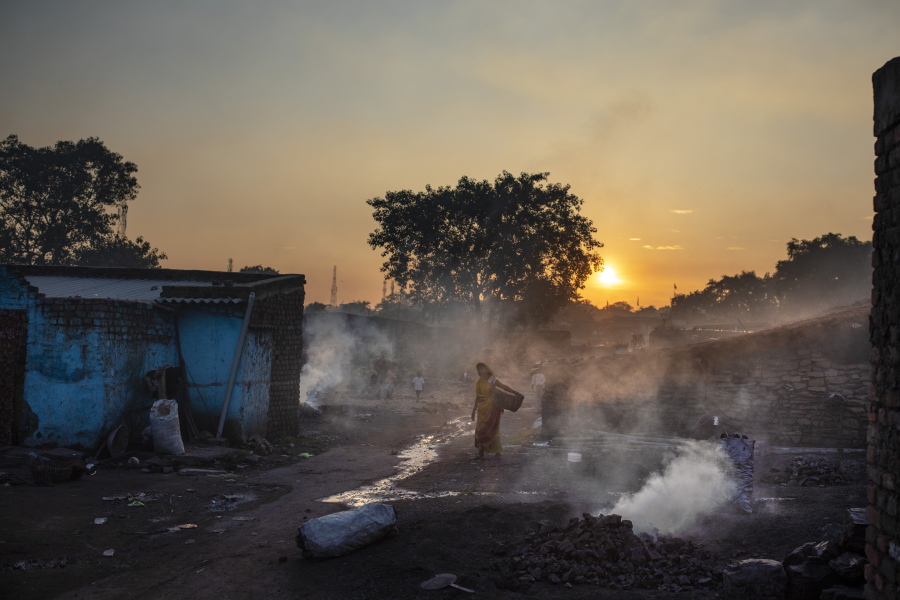 A woman walks past piles of coal burning after scavenging from an open-cast mine near Dhanbad, an eastern Indian city in Jharkhand state, Thursday, Sept. 23, 2021. On Saturday, India asked for a crucial last minute-change to the final agreement at crucial climate talks in Glasgow, calling for the "phase-down" not the "phase-out" of coal power.