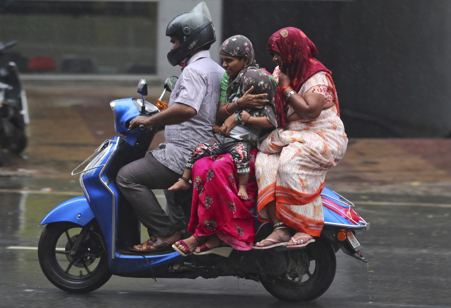 People ride a motorcycle in the rain in Hyderabad, India, Saturday, Nov. 20, 2021. More than a dozen people have died and dozens are reported missing in the southern Indian state of Andhra Pradesh after days of heavy rains, authorities said.