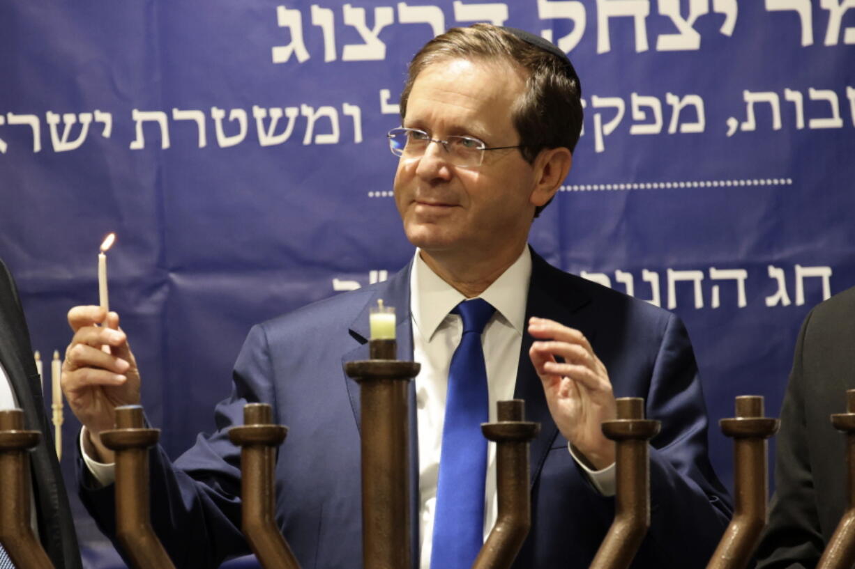 Israeli President Isaac Herzog lights candles during the Jewish holiday of Hanukkah in Hebron's holiest site, known to Jews as the Tomb of the Patriarchs and to Muslims as the Ibrahimi Mosque in the Israeli controlled part of the West Bank city of Hebron, Sunday, Nov. 28, 2021, Sunday, Nov. 28, 2021.