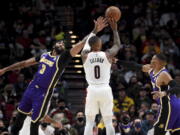 Portland Trail Blazers guard Damian Lillard, center, hits a 3-point shot from between Los Angeles Lakers Anthony Davis, left, and guard Russell Westbrook during the first half of an NBA basketball game in Portland, Ore., Saturday, Nov. 6, 2021.