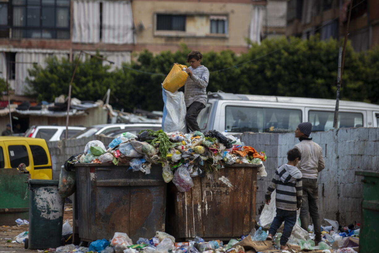 FILE - Children search for valuables in the garbage next to a market in Beirut, Lebanon, Monday, April 12, 2021. Lebanon's severe economic crisis that threw much of the population into poverty is dramatically affecting children leaving some go to bed hungry, lack good medial care and drop out of school to help their families, UNICEF, the U.N. children's agency said Tuesday, Nov. 23, 2021.