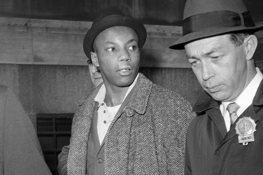 FILE -- Norman 3X Butler, 26, a suspect in the slaying of Malcolm X, is escorted by detectives at police headquarters, after his arrest, in New York, Feb. 26, 1965. Butler, one of two men convicted in the assassination of Malcolm X, is set to be cleared after more than half a century, with prosecutors now saying authorities withheld evidence in the civil rights leader's killing, according to a news report Wednesday, Nov. 17, 2021.