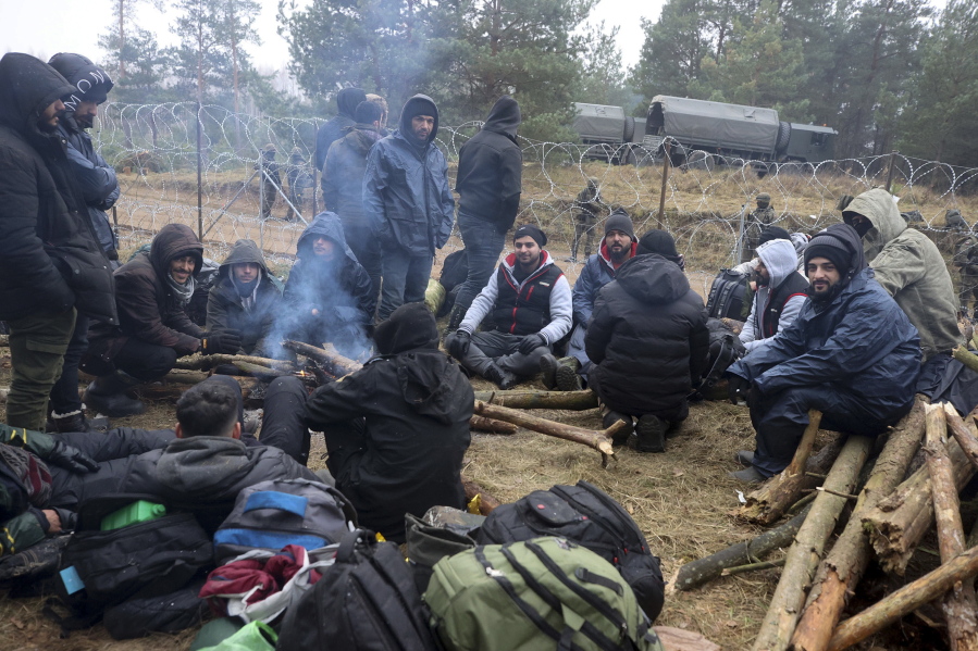 Migrants from the Middle East and elsewhere warmup at the fire gathering at the Belarus-Poland border near Grodno, Belarus, Wednesday, Nov. 10, 2021. The German government says Chancellor Angela Merkel has asked Russian President Vladimir Putin to intervene with Belarus over the migrant situation on that country's border with Poland. Merkel spoke with Putin by phone on Wednesday.