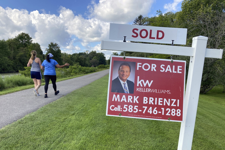 People walk by a sold sign in front of a house along the Erie Canal in Pittsford, New York, on Monday, Sept. 6, 2021. Sales of new homes jumped 14% in September to the fastest pace in six months as strong demand helped off rising prices. The Commerce Department reported Tuesday, Oct. 26, 2021 that sales of new single-family homes rose to a seasonally adjusted annual rate of 800,000 units last month after sales had fallen 1.4% in August.
