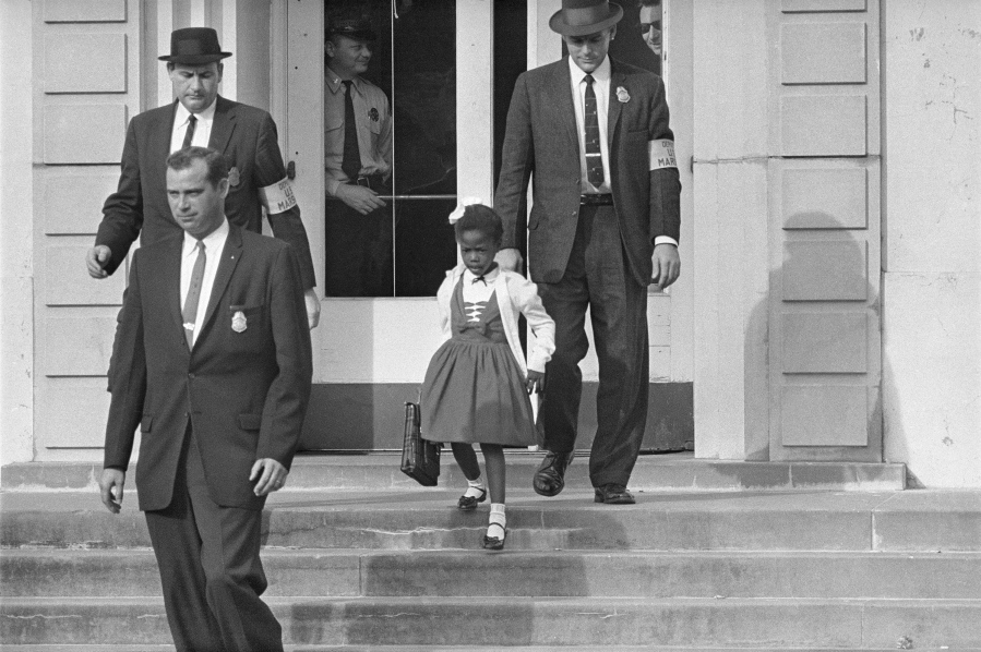 FILE - U.S. Deputy Marshals escort 6-year-old Ruby Bridges from William Frantz Elementary School in New Orleans, in this November 1960, file photo. New Orleans is marking the 61st anniversary of the integration of its public schools by four 6-year-old girls. Weekend events began with a Friday morning news conference at New Orleans City Hall and an evening screening of a video tribute to the four. A special church service and a motorcade are set for Sunday, Nov. 14, 2021.