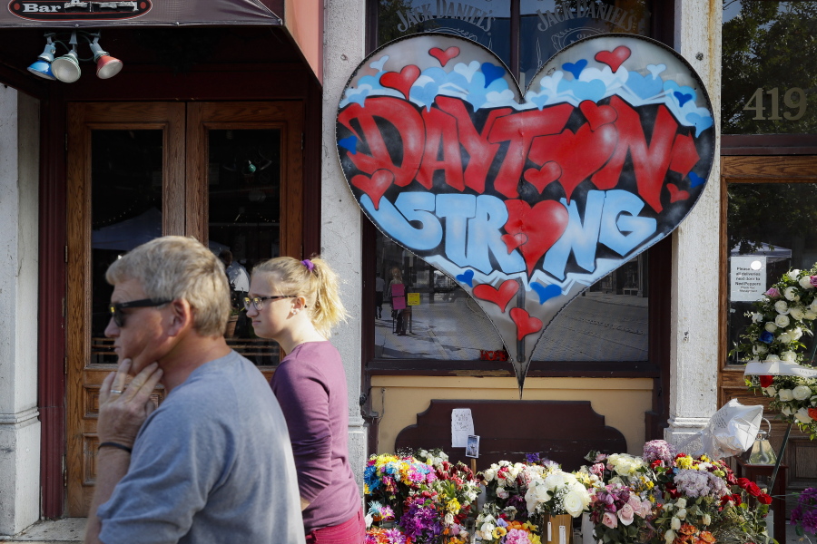 FILE - In this Aug. 7, 2019 file photo, pedestrians pass a makeshift memorial for the slain and injured victims of a mass shooting that occurred in the Oregon District in Dayton, Ohio. Relatives of four people killed when a gunman opened fire two years ago have sued the maker of a high-capacity magazine used by the shooter. The lawsuit against Nevada-based Kyung Chang Industry USA Inc. alleges negligence, negligent entrustment, and public nuisance by the company. The lawsuit filed in Nevada o n Sunday, Aug. 1, 2021 says high-capacity magazines have only one purpose: to kill multiple people as quickly as possible.