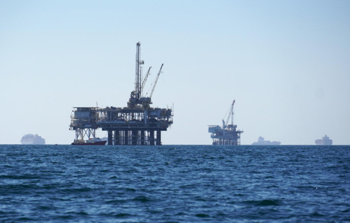 FILE - Cargo vessels are seen anchored offshore, sharing space with oil platforms, before heading into the Los Angeles-Long Beach port on Oct. 5, 2021. Oregonians are increasingly pushing for the state to divest from fossil fuel companies and other controversial investments, but the state treasury is resisting and putting the onus for any transformation on the Legislature.