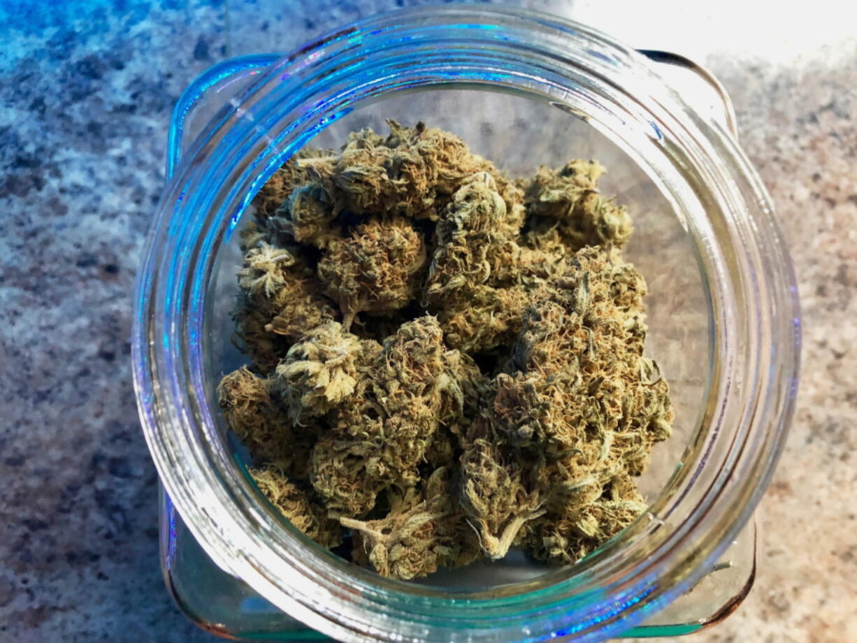 FILE - In this April 8, 2019, file photo, a jar of medical marijuana sits on the counter at a dispensary in Sherwood, Ore. Registered marijuana growers are upset that thousands of illegal marijuana farms have recently been built in southern Oregon.
