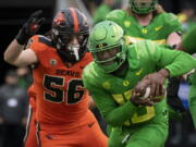 Oregon quarterback Anthony Brown (13) tries to elude the tackle of Oregon State linebacker Riley Sharp (56) during the second quarter of an NCAA college football game Saturday, Nov. 27, 2021, in Eugene, Ore.