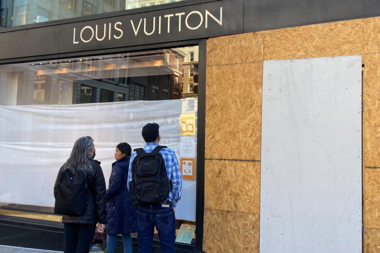 FILE - Union Square visitors look at damage to the Louis Vuitton store on Nov. 21, 2021, after looters ransacked businesses in San Francisco. Groups of thieves, some carrying crowbars and hammers, smashed glass cases and window displays, ransacking high-end stores throughout the San Francisco Bay Area, stealing jewelry, sunglasses, suitcases and other merchandise before fleeing in waiting cars during a weekend of brazen organized theft that shocked holiday shoppers and prompted concerns about the busy retail season.