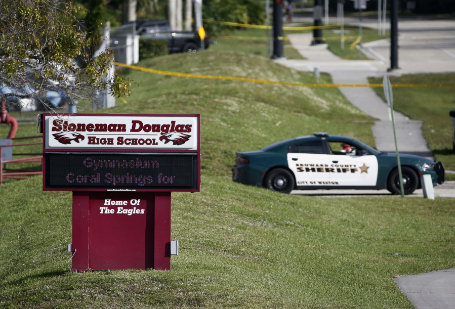 FILE- Law enforcement officers block off the entrance to Marjory Stoneman Douglas High School  Feb. 15, 2018 in Parkland, Fla., following a deadly shooting at the school. The families of most of those killed in the 2018 Florida high school massacre have settled their lawsuit against the federal government. Sixteen of the 17 killed at Marjory Stoneman Douglas High in Parkland had sued over the FBI's failure to stop the gunman even though it had received information he intended to attack. The settlement reached Monday, Nov. 22, 2021 is confidential.