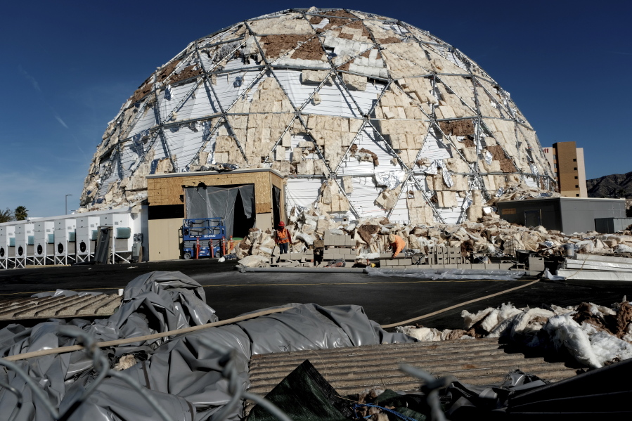 Construction workers clean up by a large dome used as a studio production facility Friday near the Burbank Airport after it was shredded by strong winds that passed through the area in Burbank, Calif.
