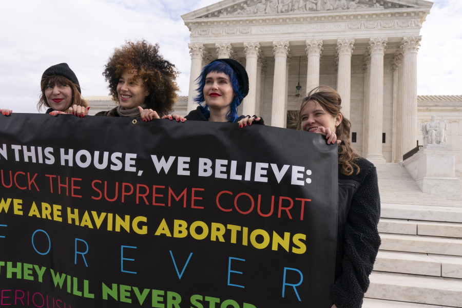 Amelia Bonow, left, with her cousin Lila Bonow, Emily Nokes, and Sara Edwards, all with the group, "Shout Your Abortion," hold a sign outside of the Supreme Court, Tuesday, Nov. 30, 2021, as activists begin to arrive ahead of arguments on abortion at the court on Capitol Hill in Washington.