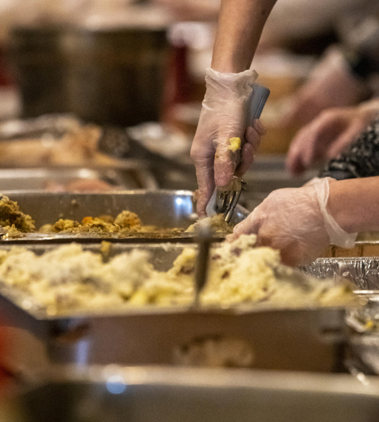 People scoop mashed potatoes, stuffing and other Thanksgiving staples into disposable tins at WareHouse '23 in Vancouver last year.