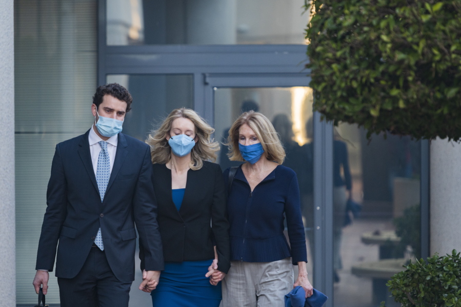 Elizabeth Holmes, center, walks into federal court in San Jose, Calif., Monday, Nov. 22, 2021. Holmes is accused of duping elite financial backers, customers and patients into believing that her startup was about to revolutionize medicine.