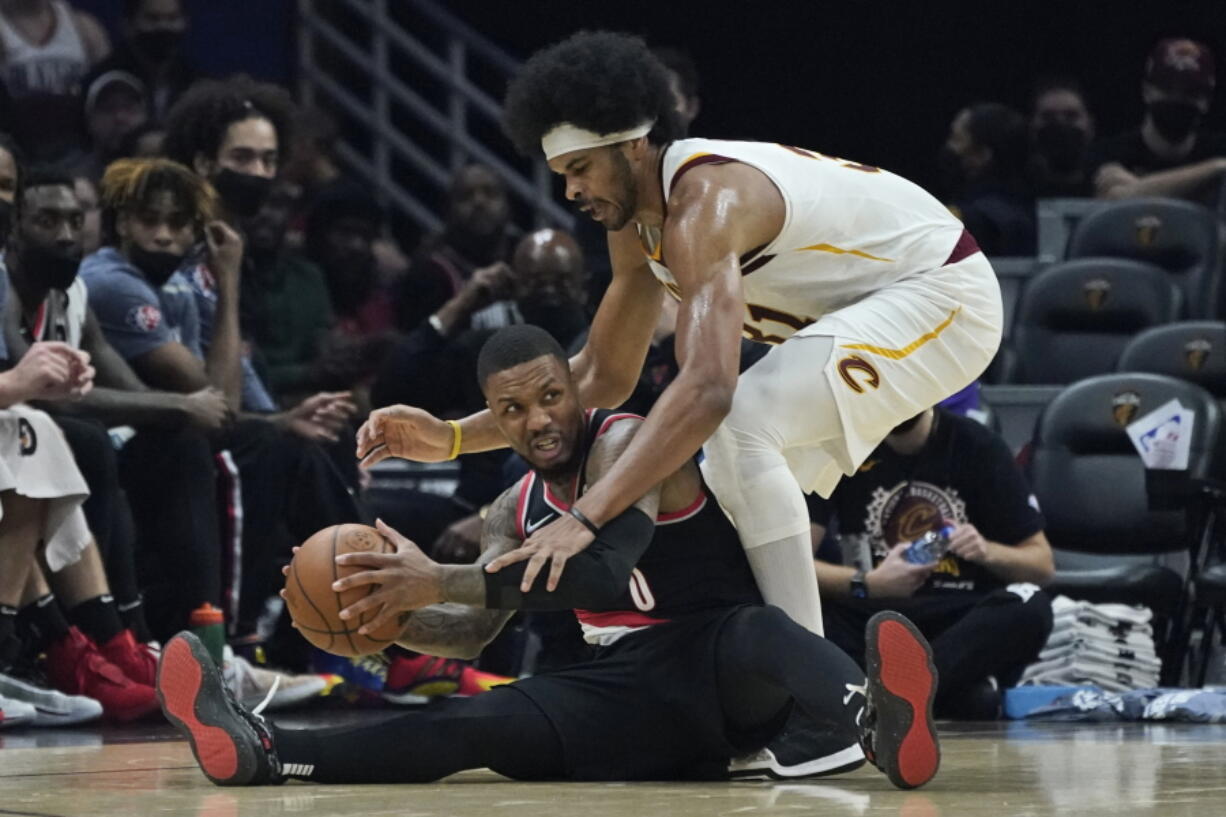 Portland Trail Blazers' Damian Lillard, bottom, looks to pass the ball as Cleveland Cavaliers' Jarrett Allen defends during the first half of an NBA basketball game Wednesday, Nov. 3, 2021, in Cleveland.