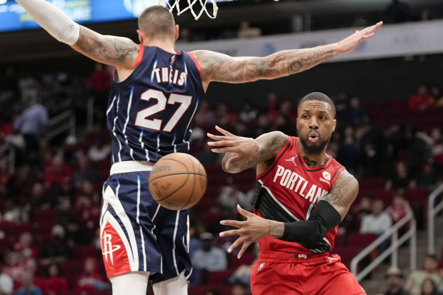 Portland Trail Blazers guard Damian Lillard, right, passes the ball as Houston Rockets center Daniel Theis defends during the first half of an NBA basketball game, Friday, Nov. 12, 2021, in Houston.