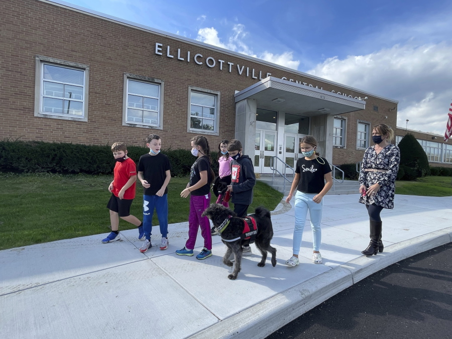Students from Ellicottville Central Schools in Ellicottville, N.Y., walk therapy dog Toby outside the rural school on Oct. 21, 2021, accompanied by the dog's owner, elementary school principal Maren Bush, right. Bush lets students walk and visit with Toby as part of the district's efforts to improve students' mental well-being, a focus of schools nationwide following pandemic disruptions.