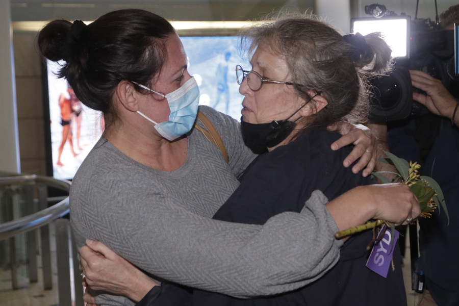 A woman, right, is embraced by. a loved-one after arriving on a flight from Los Angeles at Sydney Airport as Australia open its borders for the first time in 19 months in Sydney, Monday, Nov. 1, 2021. International travel will be initially restricted to Sydney's airport because New South Wales has the highest vaccination rate of any state.
