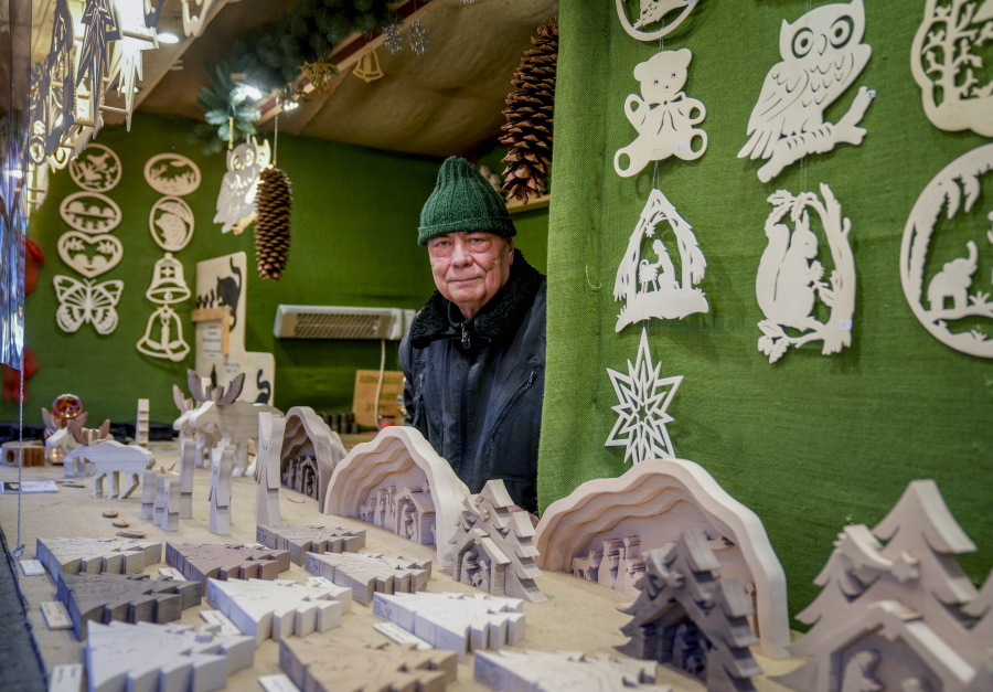 Vender Nils Knauerbstnads stands in his booth at the Christmas market in central Frankfurt, Germany, Tuesday, Nov. 23, 2021. Despite the pandemic inconveniences, stall owners selling ornaments, roasted chestnuts and other holiday-themed items in Frankfurt and other European cities are relieved to be open at all for their first Christmas market in two years, especially with new restrictions taking effect in Germany, Austria and other countries as COVID-19 infections hit record highs.