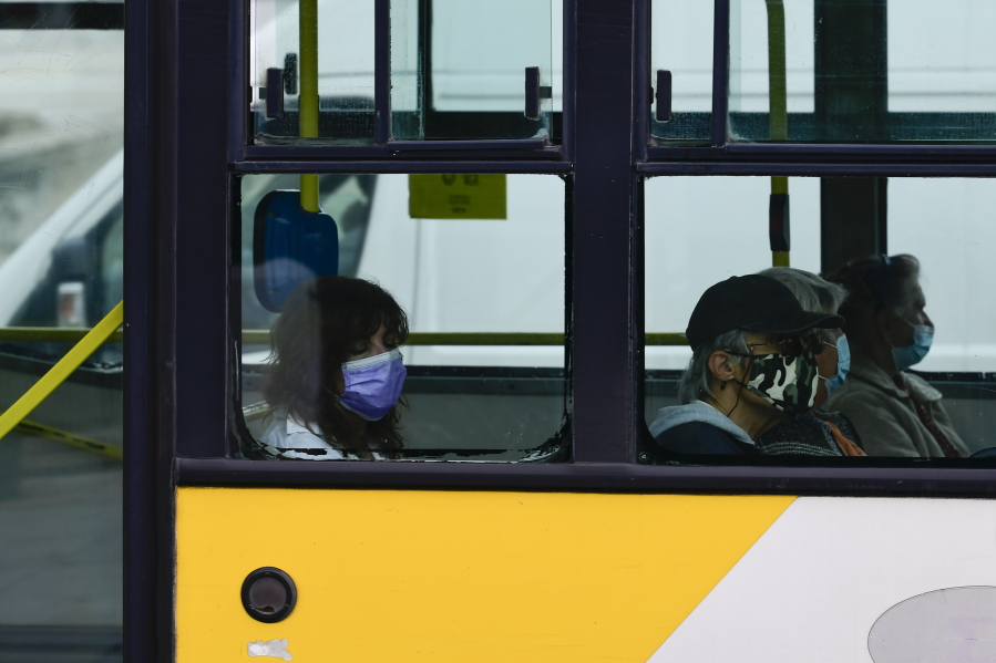 Commuters wearing face masks to curb the spread of COVID-19 are seen in a bus, in Athens, Greece, Tuesday, Nov. 9, 2021. Greece reported a new record high for daily COVID-19 infections on Monday as vaccination appointments shot up after new restrictions on unvaccinated people kicked in over the weekend.