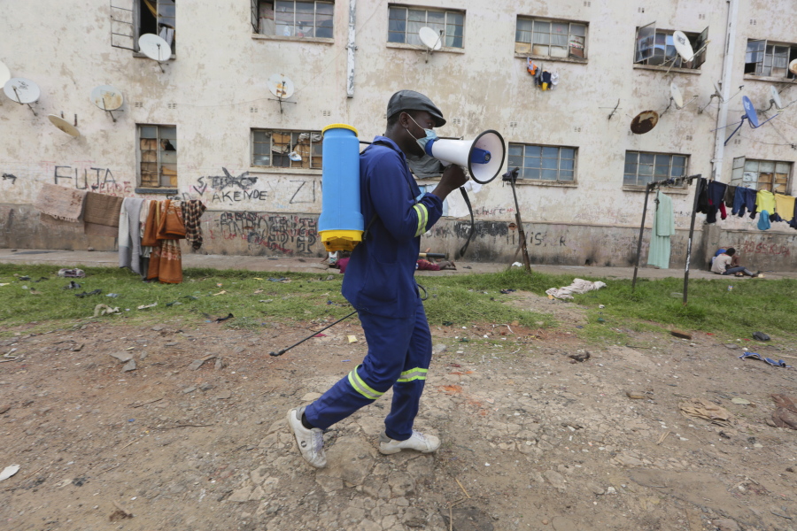 A man moves around offering fumigation services in a poor neighborhood to curb the spread of COVID-19 in Harare, Zimbabwe, Monday, Nov, 29, 2021. The emergence of the new omicron variant and the world's desperate and likely futile attempts to keep it at bay are reminders of what scientists have warned for months: The coronavirus will thrive as long as vast parts of the world lack vaccines.