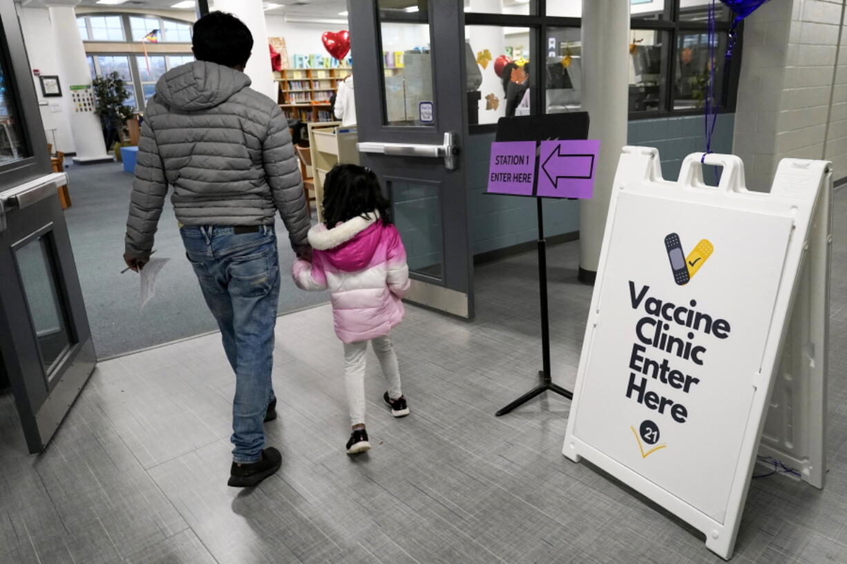An information sign is displayed as a child arrives with her parent to receive the Pfizer COVID-19 vaccine for children 5 to 11-years-old at London Middle School in Wheeling, Ill., Wednesday, Nov. 17, 2021. (AP Photo/Nam Y.