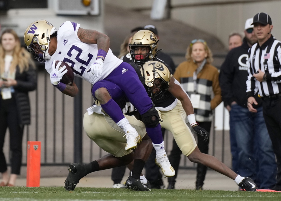 Washington running back Cameron Davis (22) is tackled by Colorado cornerback Mekhi Blackmon in the first half of an NCAA college football game Saturday, Nov. 20, 2021, in Boulder, Colo.