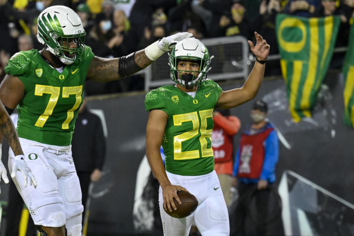 Oregon running back Travis Dye (26) celebrates his touchdown against Washington St with offensive lineman George Moore (77) during the first quarter of an NCAA college football game Saturday, Nov. 13, 2021, in Eugene, Ore.