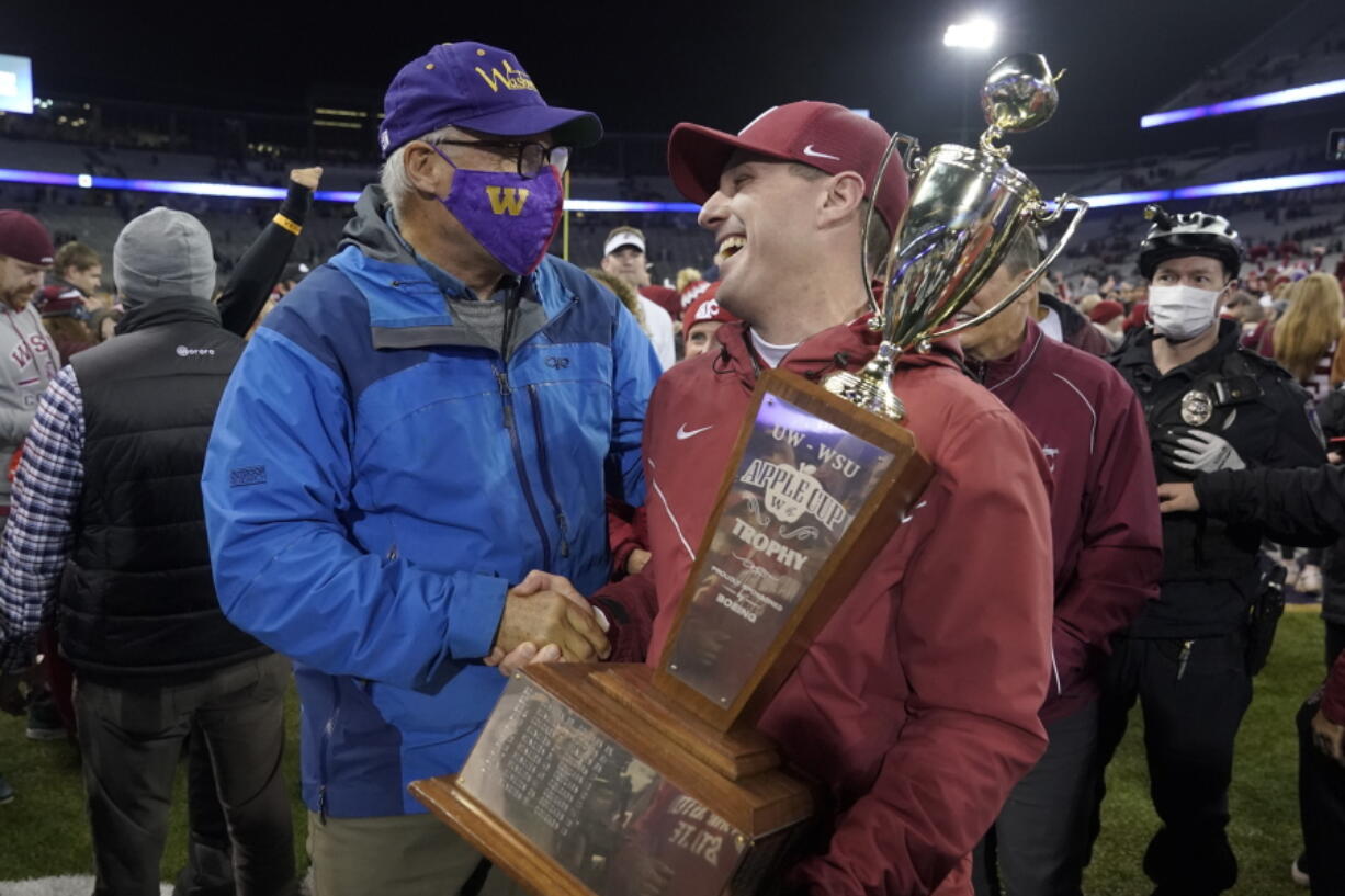 Washington State acting head coach Jake Dickert, right shakes hands with Washington Gov. Jay Inslee, left, after Inslee presented him with the Apple Cup Trophy after Washington State beat Washington 40-13 in an NCAA college football game, Friday, Nov. 26, 2021, in Seattle. (AP Photo/Ted S.