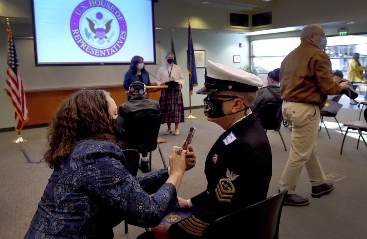 United States Navy (ret.) Chief petty officer Leroy Painter-Smith has a photo taken of his new-awarded pin by his wife Tamara as Washington state Congresswoman Marilyn Strickland (at the podium) honored 10 area veterans during a Vietnam Veterans Pinning Ceremony held at Lacey City Hall in Lacey, Wash. on Nov. 23, 2021. In partnership with the US Vietnam Veterans Pin Commission the ceremony honored local veterans and is associated with an ongoing effort nationally to honor all Vietnam War period veterans who served from November 1, 1955, to May 15, 1975. He served aboard the carrier USS Constellation in the Vietnam conflict and retired from the service in 1989.