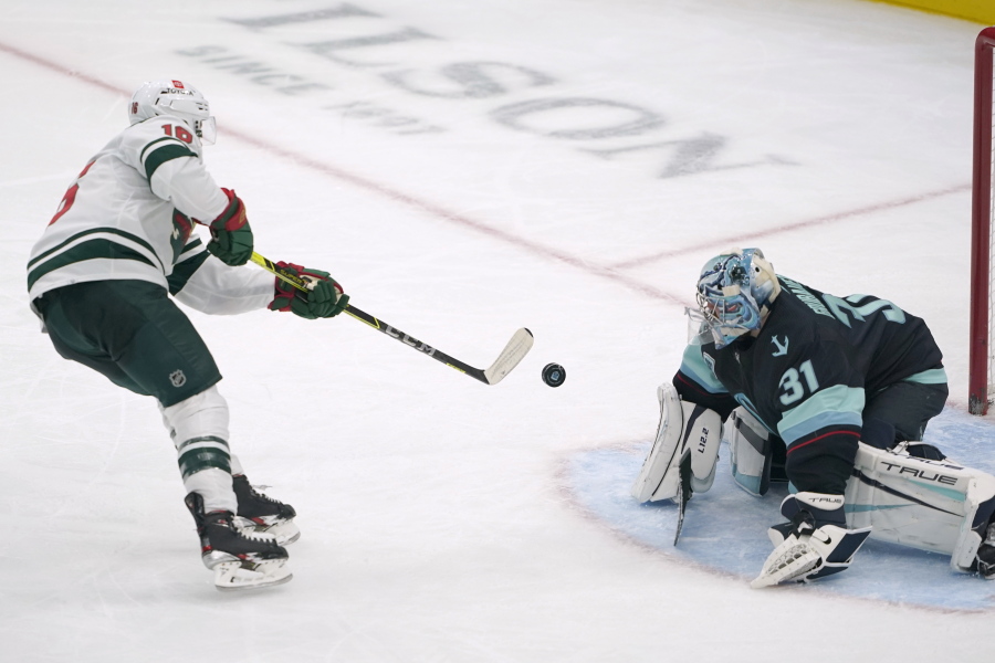 Minnesota Wild center Rem Pitlick, left, scores a goal on Seattle Kraken goaltender Philipp Grubauer (31) during the second period of an NHL hockey game Saturday, Nov. 13, 2021, in Seattle. The goal was Pitlick's first of two goals in the second period. (AP Photo/Ted S.