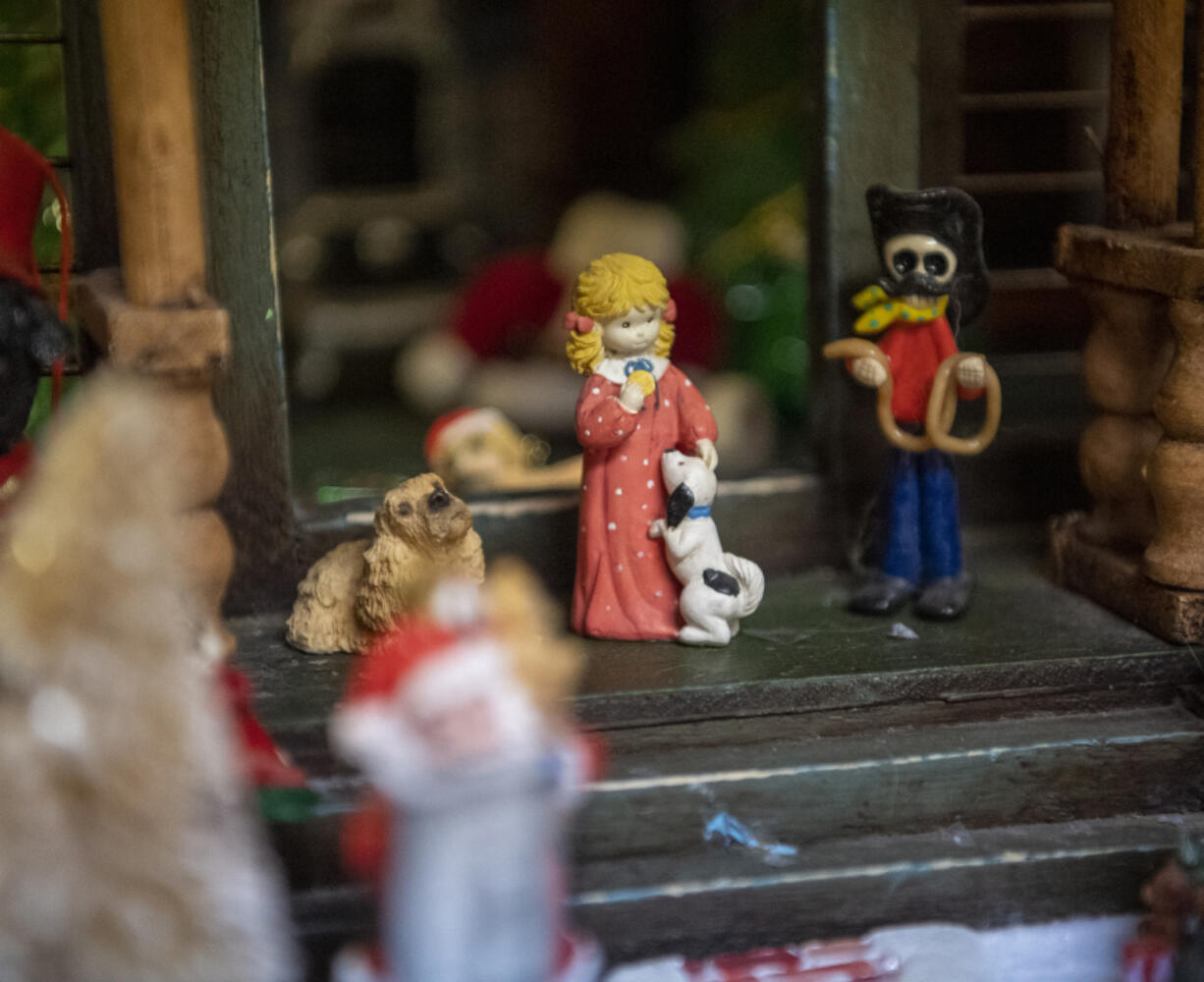 A small figurine of a person and a dog sits in front of a decorated dollhouse on at Susie's Country Inn for Dogs and Cats on Northeast 159th Street near Brush Prairie.