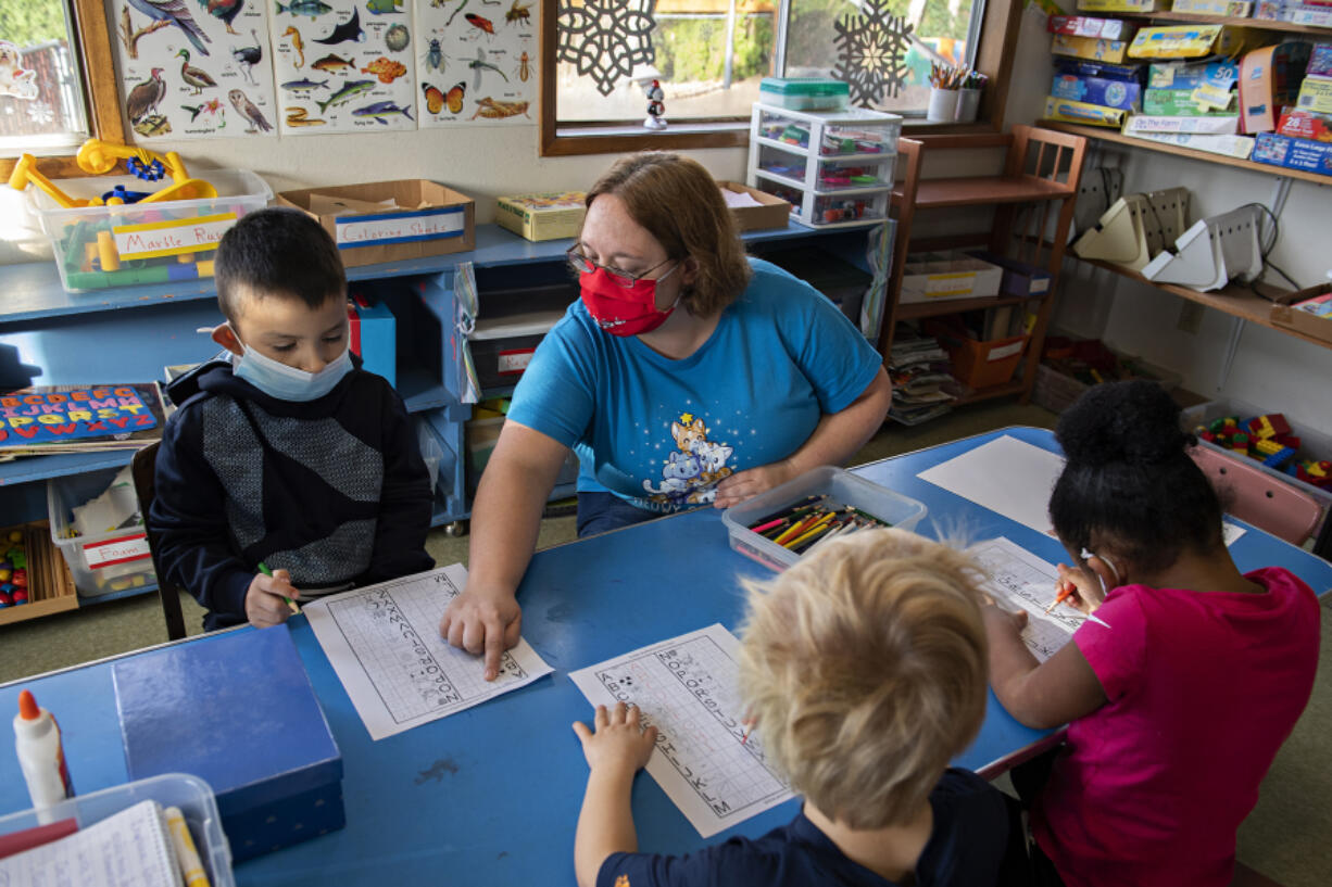 Julian Gomez, 5, left, works with teacher Sandy Becker, red mask, as he learns the letters of the alphabet at Jack and Jill House on Thursday morning. The day care is one of Clark County's 86 licensed child care centers.