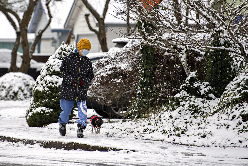 Cindy Steffen of Battle Ground keeps in step with her dog, Hato, 2, as they enjoy a brisk but scenic walk around their neighborhood Monday morning, Dec. 27, 2021. Forecasters predict the cold temperatures and chance of snow will stick around for most of the week.