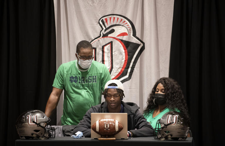 Dom Merriweather, from left, looks on as his son, Tobias Merriweather, an incoming senior at Union High School, announces he will play college football at Notre Dame while joined by Tobias' mother, Beverly Merriweather, at Union High School on Wednesday afternoon, Aug. 4, 2021.